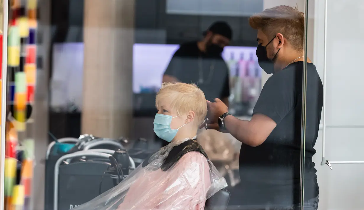 Seorang barber memotong rambut pelanggan di Berlin, Jerman (9/5/2020). Kanselir Jerman Angela Merkel mengatakan bahwa pembatasan terkait COVID-19 akan dilonggarkan, sementara peraturan kebersihan dan jaga jarak sosial (social distancing) minimum akan terus diberlakukan. (Xinhua/Binh Truong)