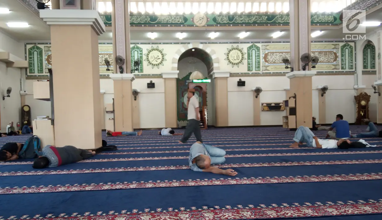 Seorang pria melintas di antara jemaah yang sedang tidur-tiduran di Masjid Agung Baiturrahim, Provinsi Gorontalo, Sabtu (11/5/2019). Sebagian umat muslim menghabiskan waktu dengan tidur di masjid atau melakukan tadarus Alquran pada siang hari selama bulan Ramadan. (Liputan6.com/Arfandi Ibrahim)
