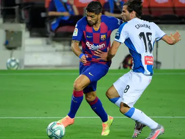 Penyerang Barcelona, Luis Suarez berebut bola dengan bek Espanyol, Leandro Cabrera pada lanjutan pertandingan La Liga Spanyol di Camp Nou, Kamis (9/7/2020) dini hari WIB.  Barcelona menang tipis 1-0 atas Espanyol lewat gol yang dicetak Luis Suarez. (LLUIS GENE / AFP)