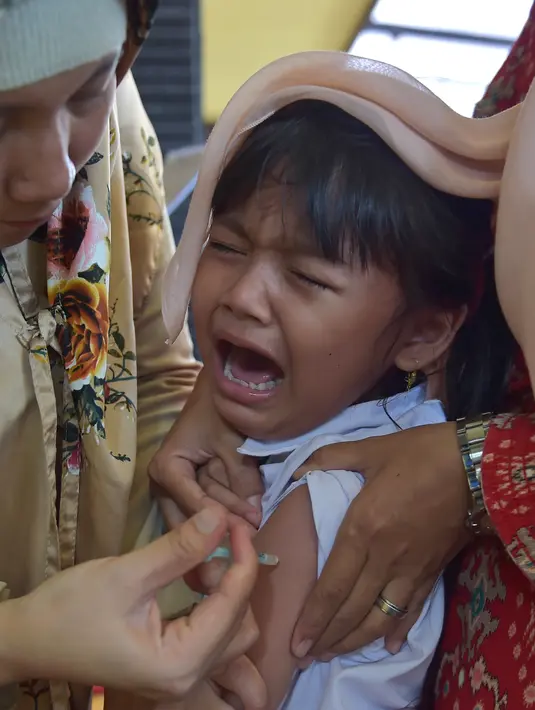 Seorang anak menangis saat disuntik vaksin difteri di sebuah klinik desa di Jakarta (11/12). Wabah Difteri ini telah menewaskan puluhan orang. (AFP Photo/Adek Berry)