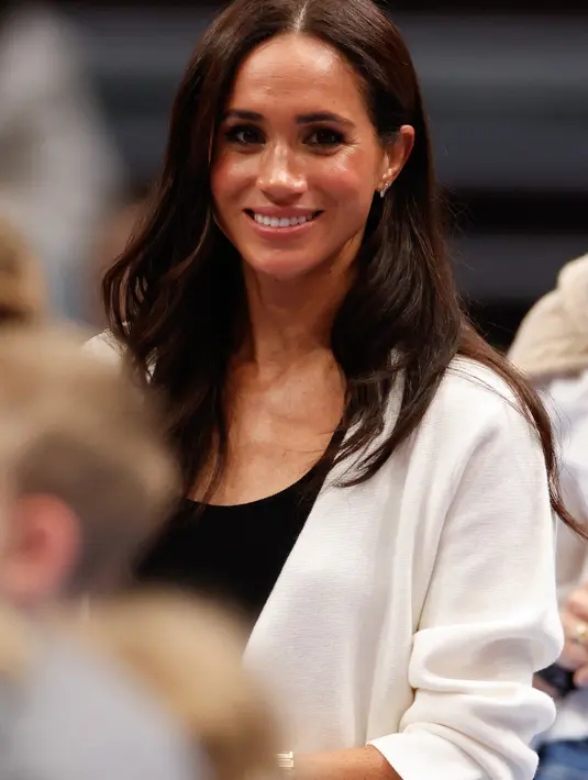 Meghan Markle juga terlihat memakai aksesori berupa cincin warna pink serta gelang dan jam tangan emas. (Odd ANDERSEN / AFP)
