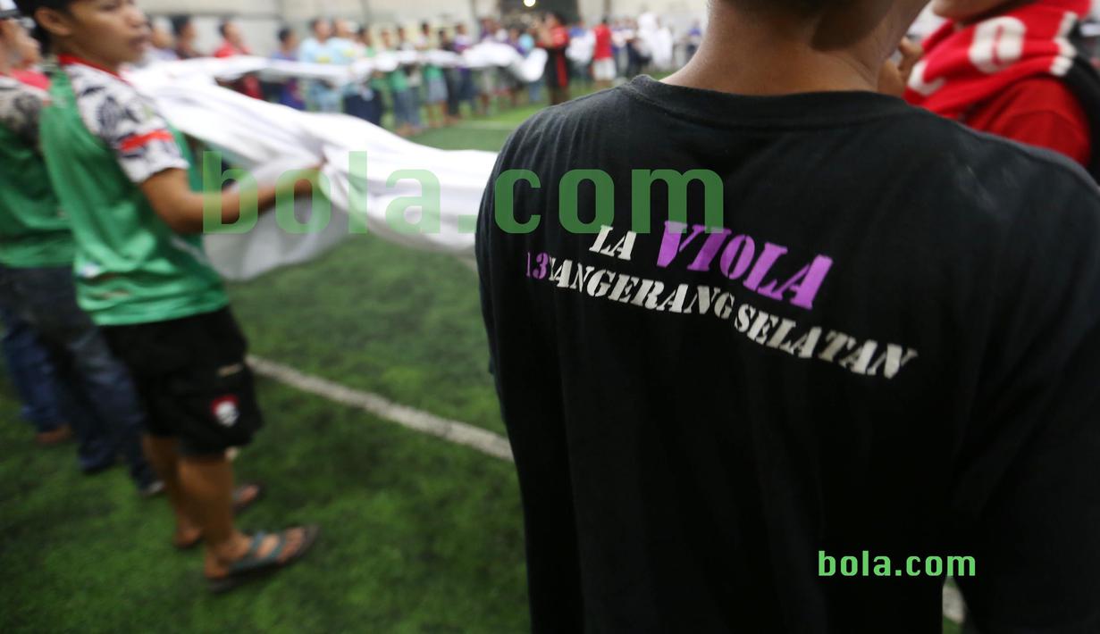 Suporter menggulung bendera Merah-Putih raksasa di Tangerang, Sabtu (31/10/2015). Selain ingin mencatat rekor dunia, tema dasar adalah "One Soul, One Nation Untuk Sepakbola Indonesia".  (Bola.com / Nicklas Hanoatubun).
