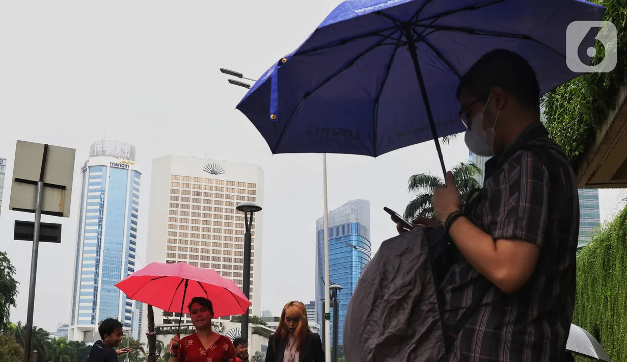 Warga menggunakan payung saat hujan mengguyur kawasan Jakarta, Senin (3/2/2020). Badan Meteorologi, Klimatologi, dan Geofisika (BMKG) merilis informasi peringatan dini cuaca ekstrem yang diperkirakan berlangsung hingga Rabu (5/2/2020) mendatang. (Liputan6.com/Angga Yuniar)