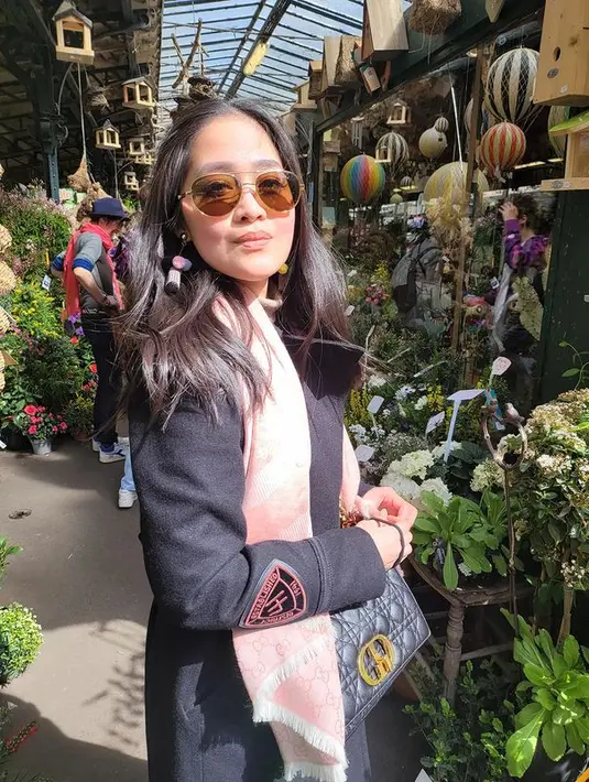 Liburan di Paris, Gracia Indri tampil fashionable dengan memadukan coat berwarna hitam dan syal pink. Bergaya ala Parisian, ia pun memadukannya dengan tartan skirt legging, serta tas dari Christian Dior.
 (instagram/graciaz14)
