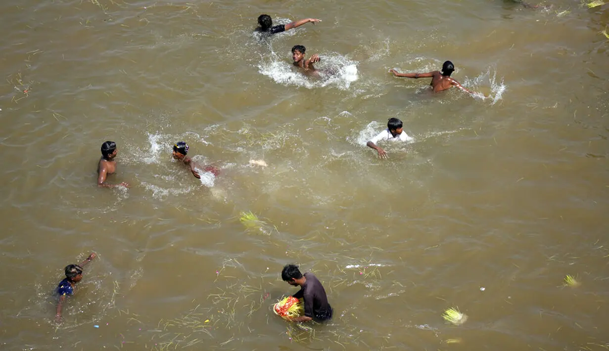 Anak-anak mencari koin saat umat Hindu mencelupkan bibit jelai sebagai persembahan saat Festival Navratri di Sungai Tawi, Jammu, India, 10 April 2022. Sesaji tersebut dibuat sebagai bagian dari ritual menandai berakhirnya festival selama sembilan hari. (AP Photo/Channi Anand)
