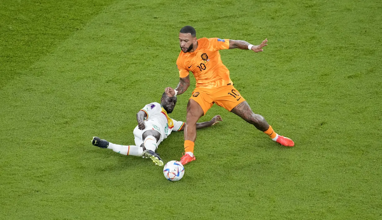 Penyerang Belanda, Memphis Depay berusaha melewati pemain Senegal, Iliman Ndiaye pada pertandingan grup A Piala Dunia 2022 Qatar di Stadion Al Thumama di Doha, Qatar, Senin (21/11/2022). Kemenangan ini membuat Belanda sementara memuncaki klasemen Grup A, satu tingkat di atas Ekuador yang sehari sebelumnya menundukkan tuan rumah Qatar dengan skor serupa, 2-0. (AP Photo /Thanassis Stavrakis)
