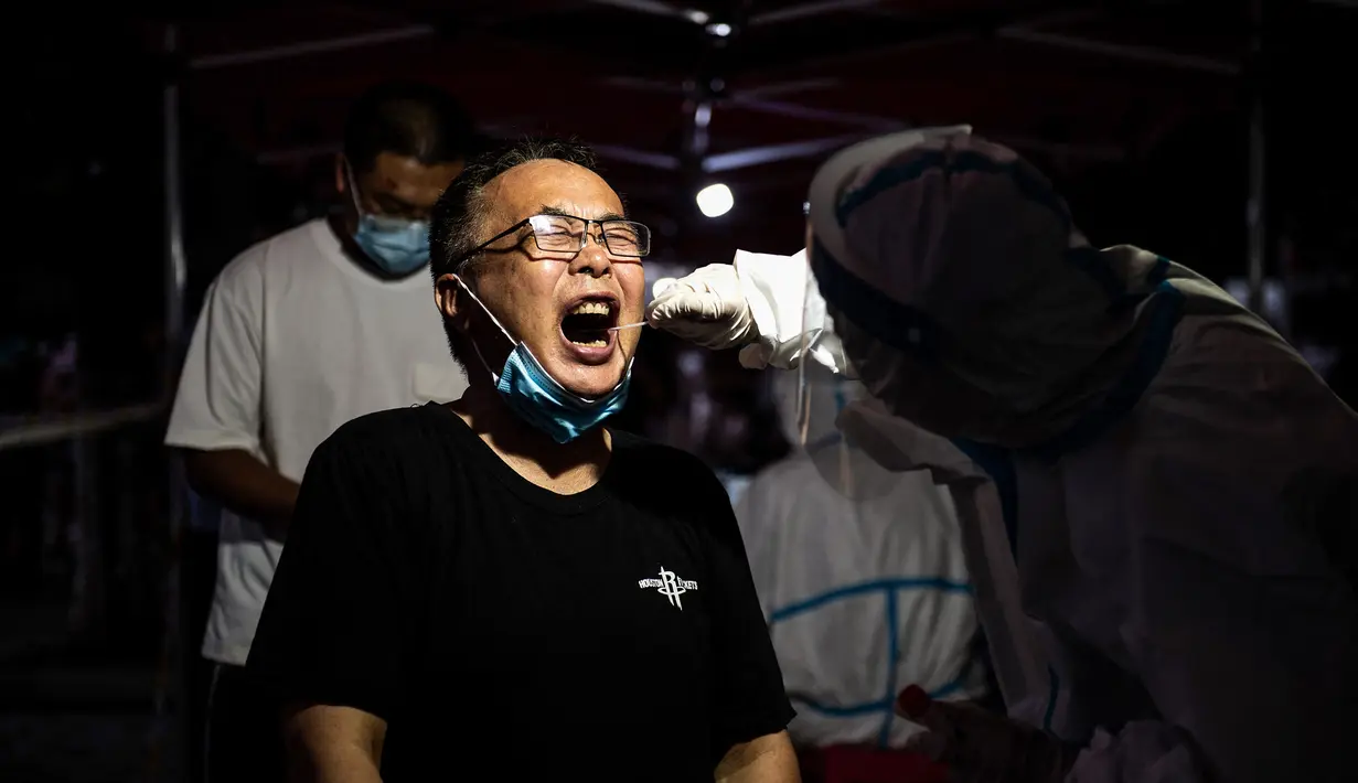 Seorang warga menerima tes asam nukleat untuk virus corona di Wuhan di provinsi Hubei tengah China (3/8/2021).Langkah tersebut dilakukan setelah sejumlah kota di China melaporkan infeksi lokal pertamanya setelah lebih dari setahu . (AFP/STR)