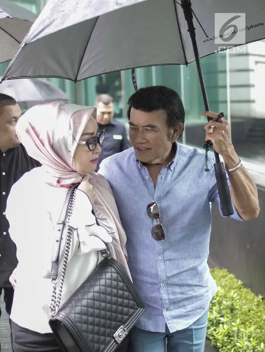 Rhoma Irama memayungi istrinya Ricca Rachim saat hadir dalam konferensi pers indosiar Ramadhan Penuh Berkah di Jakarta, Kamis (26/4). (Liputan6.com/Faizal Fanani)