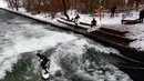 Seorang pria menaklukkan ombak saat berselancar di Sungai Eisbach selama hari musim dingin di Munich, Jerman, 4 Januari 2017. Sungai ini dipakai sebagai tempat berselancar sejak 1972 namun baru secara resmi diperbolehkan pada 2010. (Mark RALSTON/AFP)