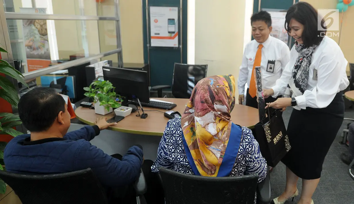 Pimpinan cabang Okky Arief Prakoso (kedua kanan) bersama staf memberikan setangkai bunga mawar dan souvenir dalam rangka HUT ke 72 BNI kepada nasabah di Kantor Cabang BNI Tebet, Jakarta (5/7). (Merdeka.com/Arie Basuki)