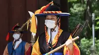 Anggota 'penjaga istana' yang mengenakan masker berdiri untuk turis di gerbang utama Istana Deoksugung di Seoul (4/9/2020). Korea Selatan melaporkan 198 kasus Covid-19 baru pada 4 September, hari ke-22 berturut-turut meningkat tiga digit. (AFP/Jung Yeon-je)