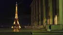 Seorang wanita mengajak anjingnya berjalan-jalan selama jam malam di Trocadero yang kosong, dekat Menara Eiffel, Paris, Perancis, Selasa (15/12/2020). Tingkat infeksi COVID-19 di Prancis telah menurun tajam sejak puncak gelombang kedua bulan lalu. (AP Photo/Francois Mori)
