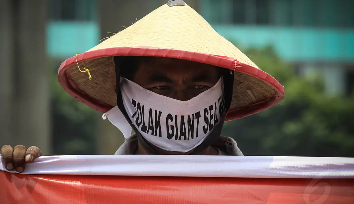 Seorang pengunjuk rasa tampak memakai penutup wajah yang bertuliskan tolak Giant Sea Wall, Jakarta, (15/10/14).(Liputan6.com/Faizal Fanani)
