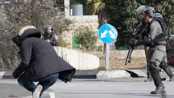 Seorang pria Palestina terjatuh usai ditembak dari jarak dekat oleh polisi Israel di dekat Ramallah, Tepi Barat, Jumat (15/12). Pemuda ini ditembak usai menikam tentara perbatasan Israel. (AFP Photo/Oren Ziv)