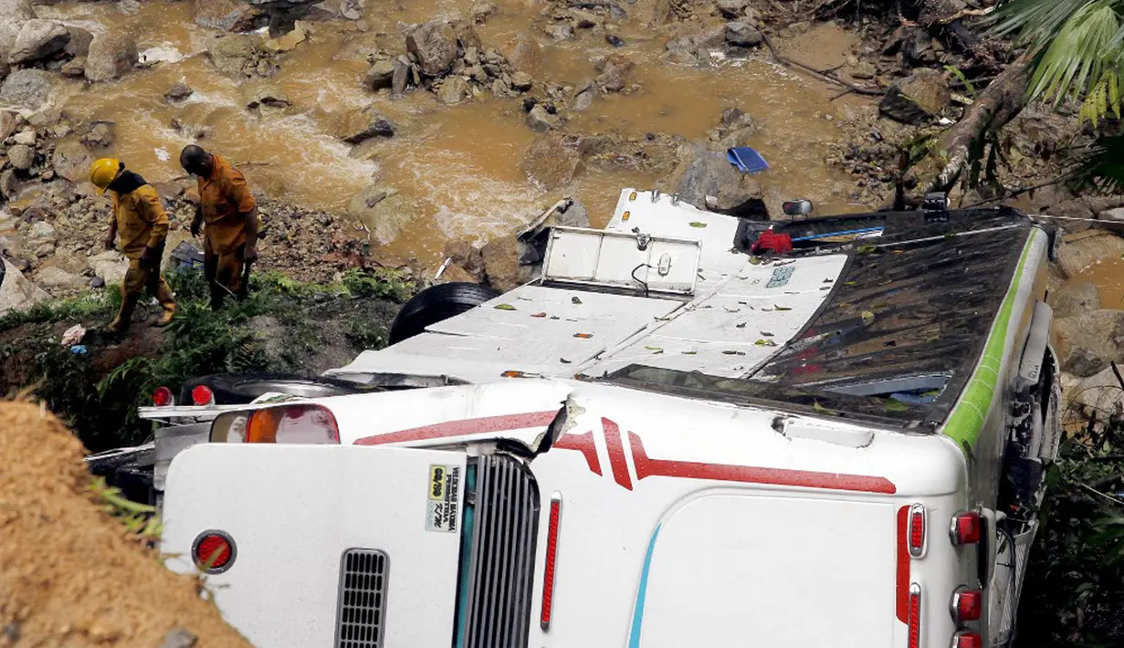 Petugas penyelamat berjalan dekat bus yang jatuh di jalan penghubung Medellin dan Bogota dekat San Luis, Provinsi Antiokia, Kolombia, 27 Desember 2021. Tujuh orang, termasuk seorang wanita hamil, tewas dan 20 lainnya luka-luka ketika sebuah bus terjun ke jurang. (Fredy BUILES/AFP)