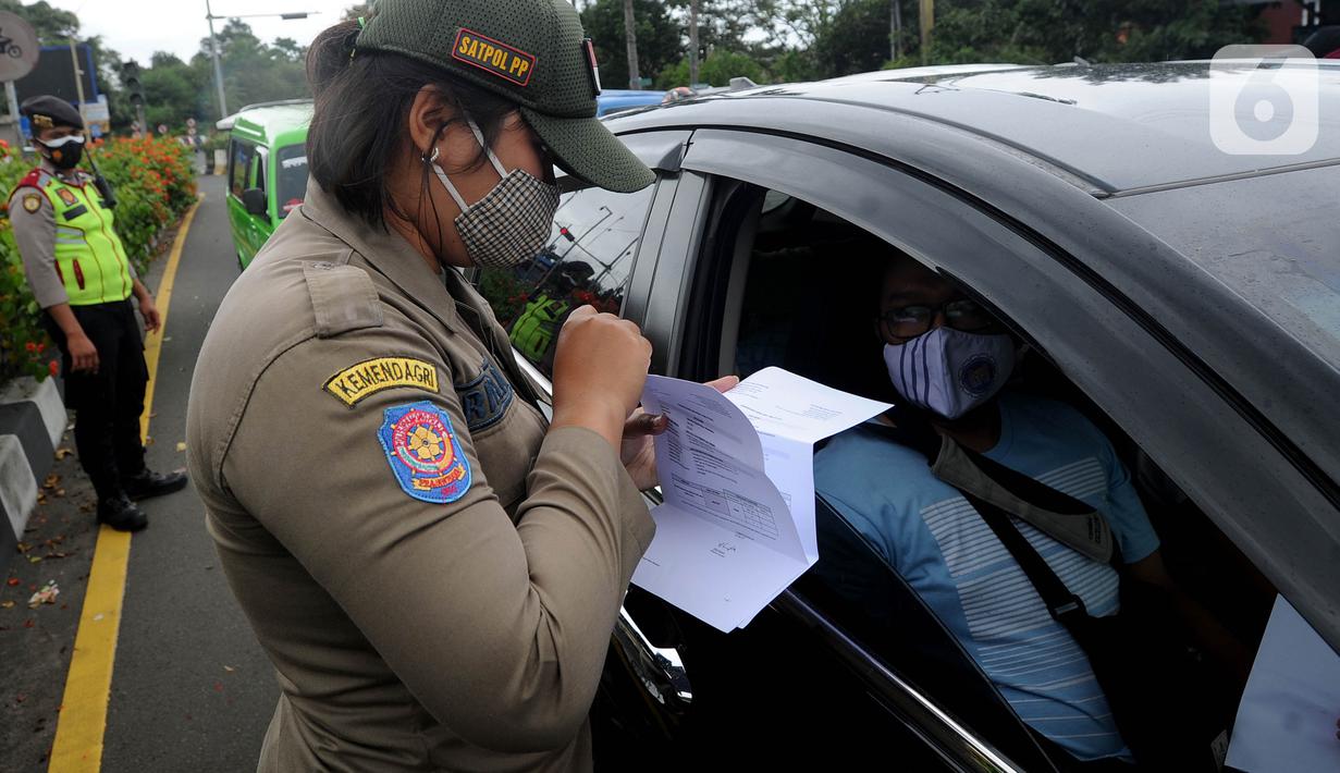 Petugas gabungan memeriksa surat hasil tes cepat antigen terhadap pengendara mobil di Simpang Gadog, Bogor, Kamis (24/12/2020). Pemkab Bogor mewajibkan para wisatawan menunjukkan hasil tes cepat antigen sebagai upaya mencegah penyebaran COVID-19 di saat libur Tahun Baru. (merdeka.com/Arie Basuki)