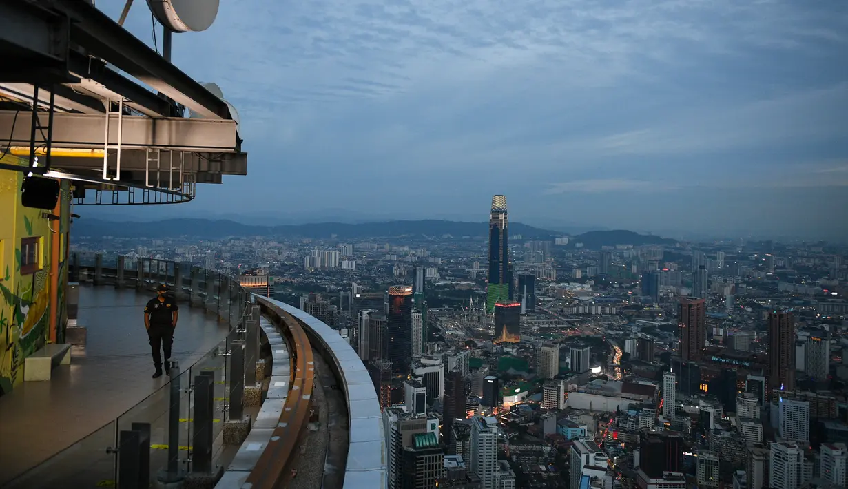 Seorang penjaga keamanan berpatroli di sepanjang Menara KL di Kuala Lumpur (13/10/2020). Malaysia tengah memerangi lonjakan baru kasus virus corona baru COVID-19. (AFP/Mohd Rasfan)