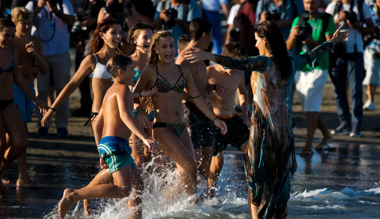 Model Isabeli Fontana menyapa pengunjung pantai selama Festival film Venice ke-74 di Venice, Italia (30/8). Model 34 tahun ini tampil dengan gaun transparan saat sesi pemotretan di pantai. (AP Photo / Domenico Stinellis)