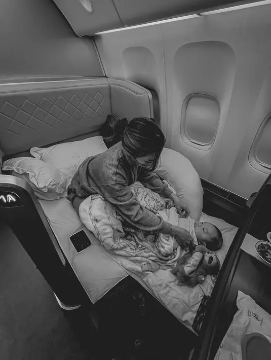 Foto ketiga menampilkan Nikita Willy tengah membetulkan baju dan selimut baby Issa yang berbaring di ranjang berukuran mini, salah satu fasilitas dalam pesawat kelas atas. “And just like that, we’re coming back home as a family of 3 (Dan begitulah, kami akan pulang ke rumah sebagai keluarga kecil terdiri tiga orang),” beri tahu Nikita Willy bersama foto ini. (Foto: Dok. Instagram @nikitawillyofficial94)