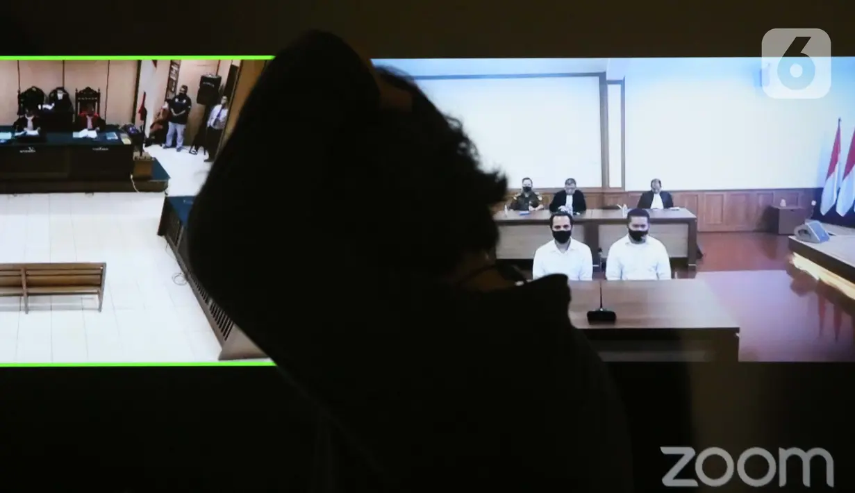 Pengunjung melintasi layar monitor yang menampilkan dua terdakwa penyiraman air keras terhadap penyidik KPK Novel Baswedan, Rahmat Kadir Mahulette (kanan) dan Rony Bugis yang mengikuti sidang putusan secara teleconference di PN Jakarta Utara, Kamis (16/7/2020). (Liputan6.com/Helmi Fithriansyah)