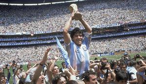 Penyerang Argentina, Diego Maradona, mengangkat trofi Piala Dunia saat usai mengalahkan Jerman Barat pada laga final Piala Dunia 1986 di Meksiko, (29/6/1986). (Photo by - / AFP)