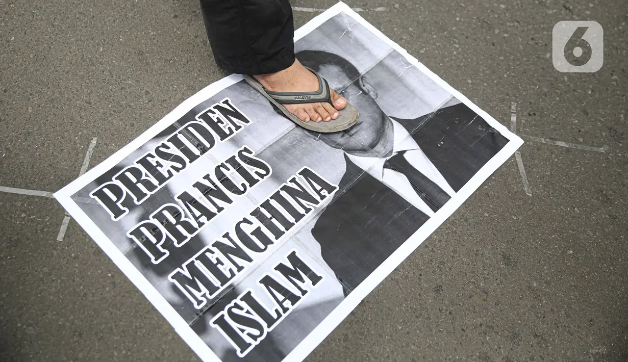 Pengunjuk rasa berdiri di atas poster bergambar Presiden Prancis Emmanuel Macron dalam aksi damai di kawasan Sarinah, Jakarta, Senin (2/11/2020). Massa demonstran dari gabungan elemen Islam mengecam pernyataan presiden Emmanuel Macron yang dianggap menghina Islam. (Liputan6.com/Faizal Fanani)