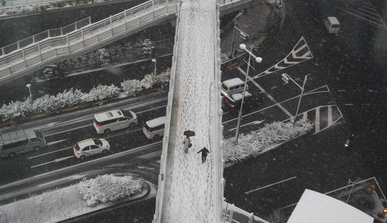 Orang-orang berjalan di atas salju di Tokyo, Kamis (6/1/2022). Badan Meteorologi mengeluarkan peringatan untuk salju lebat di Tokyo pada hari Kamis karena tekanan rendah dan penurunan suhu membawa hujan salju ke area yang luas di pantai Pasifik negara itu. (AP Photo/Koji Sasahara)