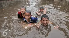 Sejumlah anak di kawasan Kemang Utara memanfaatkan banjir untuk bermain, Jakarta, Rabu (20/7). Akibat intensitas hujan deras yang mengguyur Jakarta, sejumlah ruas jalan tergenang air. (Liputan6.com/Yoppy Renato)