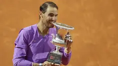 Petenis Spanyol, Rafael Nadal menggigit trofi juara turnamen tenis Italia Terbuka 2021 setelah mengalahkan petenis Serbia, Novak Djokovic di Foro Italico, Roma, Minggu (16/5/2021). Rafael Nadal menang dalam pertarungan tiga set 7-5, 1-6, dan 6-3 selama dua jam 49 menit. (AP Photo/Gregorio Borgia)