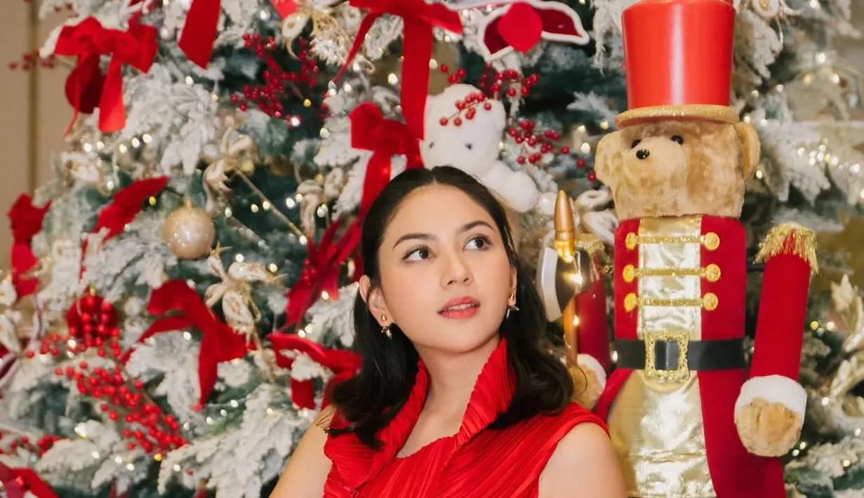 Berpose di depan pohon Natal, Jessica Mila kenakan pleated dress merah yang anggun effortless. Rambutnya ditata half updo yang pancarkan aura cantik natural [@jscmila]