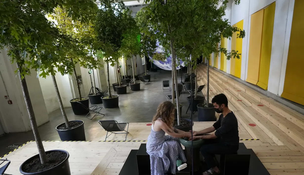 Pengunjung berpartisipasi dalam instalasi 'Cuci Tangan' di pusat budaya Base, di Milan, Italia (15/6/2021). Pengunjung bisa saling mencuci tangan dengan sabun untuk menjalin kontak fisik yang aman. (AP Photo/Luca Bruno)