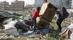 Warga membawa barang yang masih bisa terpakai di tempat pengungsian korban gempa bumi di Chuchepati, Kathmandu, Nepal, Selasa (14/3). Pemerintah Nepal terpaksa menggusur kamp ini karena sudah berdiri selama dua tahun. (AP Photo)
