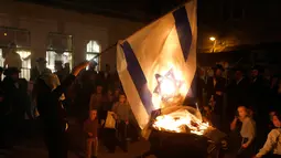 Seorang Yahudi ultra ortodoks antizionis membakar bendera Israel di Yerusalem ultra-Ortodoks Mea Shearim, Rabu (2/5). Upacara ini menandai peringatan kematian Rabbi Talmudic Rabbi Shimon Bar Yochai sekitar 1.900 tahun lalu. (MENAHEM KAHANA / AFP)