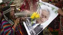 Dukun Peru menyemprotkan air ke foto Presiden Meksiko Andres Manuel Lopez Obrador saat memberikan prediksi untuk 2022 dalam ritual tradisional sebelum Malam Tahun Baru di bukit San Cristobal di Lima, Peru  (29/12/2021). (AFP/Ernesto Benavides)