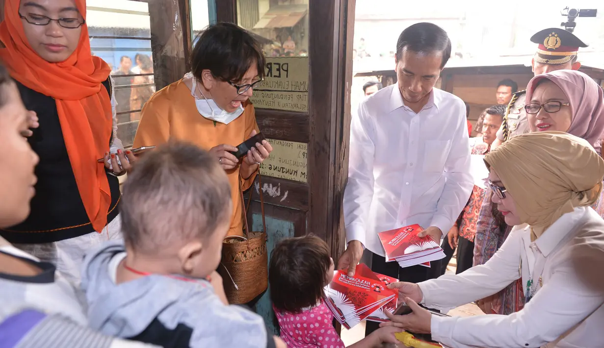 Presiden Jokowi membagikan sejumlah buku saat meninjau rumah evakuasi balita di kawasan 5 Ulu, Palembang, Sumsel, Jumat (30/10). Jokowi melihat langsung kondisi rumah evakuasi balita yang terpapar kabut asap. (Laily Rachev_Setpres)