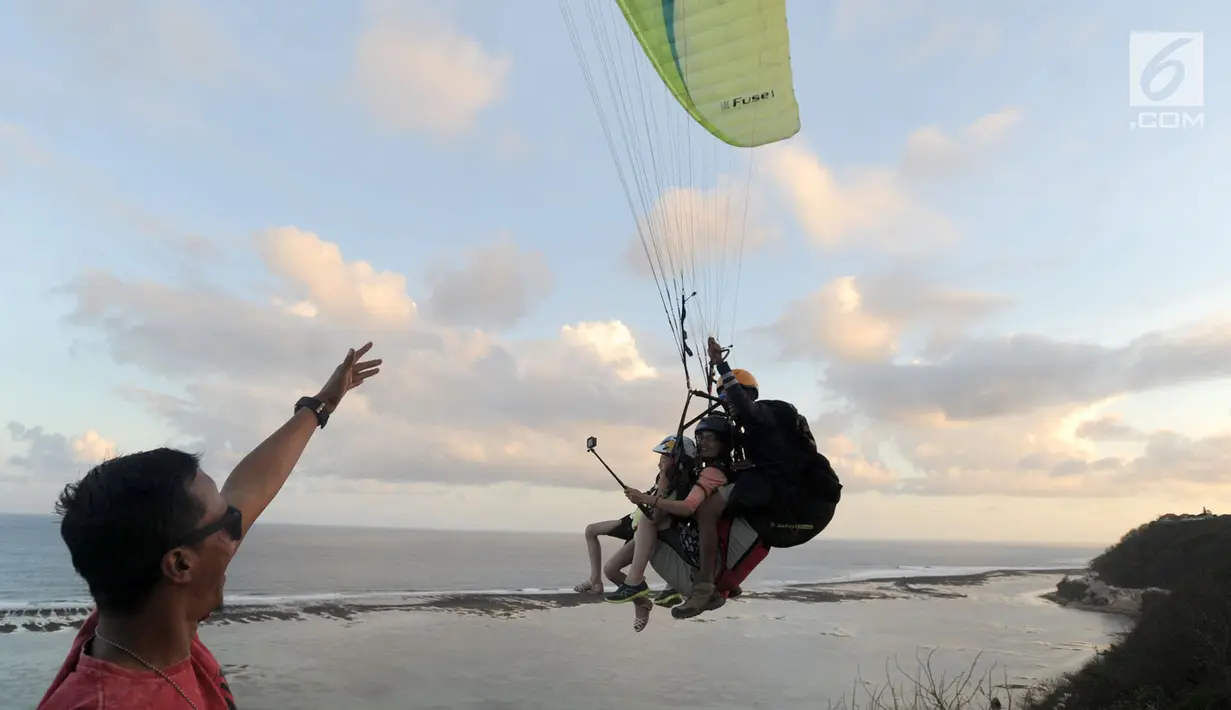 Dua wisatawan asal China melakukan tandem paralayang yang difasilitasi operator Riug Paragliding di Bukit Riug, Nusa Dua, Bali (30/6). Setiap wisatawan dikenai tarif 110 dollar/ orang untuk penerbangan selama 15 menit. (Merdeka.com/Arie Basuki)