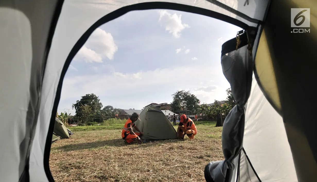 Petugas PPSU mendirikan tenda di Cipinang Melayu, Jakarta, Minggu (30/12). Pendirian puluhan tenda di RTH tersebut untuk kemah massal dalam menyambut malam Tahun Baru yang juga diisi dengan kegiatan doa bersama. (Merdeka.com/ Iqbal S. Nugroho)