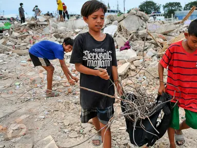 Dua orang anak membawa sisa-sisa besi dari reruntuhan bangunan yang dirobohkan di kawasan Pasar Ikan, Penjaringan, Jakarta, Selasa (12/4). Selain warga, sejumlah pemulung besi berhambur untuk menjarah besi dari bekas bangunan (Liputan6.com/Yoppy Renato)