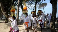 Umat Hindu membawa persembahan saat upacara Melasti menjelang Hari Raya Nyepi di Pantai Kuta, Bali (11/3/2021). Upacara Melasti dilakukan oleh perwakilan desa adat dengan jumlah terbatas serta menerapkan protokol kesehatan untuk mencegah penyebaran pandemi COVID-19. (AFP/Sonny Tumbelaka)