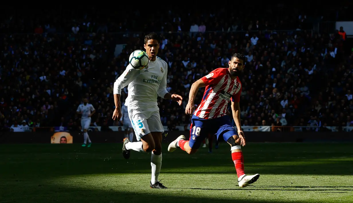 Pemain Real Madrid Varane berebut bola dengan pemain Atletico Madrid Diego Costa saat pertandingan La Liga Spanyol di stadion Santiago Bernabeu di Madrid (8/4). (AP Photo / Francisco Seco)