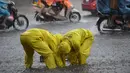 Dua petugas kota membuka selokan di jalan yang banjir setelah badai tropis Talas terjadi di Hanoi, Vietnam utara (17/7). Kondisi cuaca ini disebabkan adanya Badai Talas di perairan Laut Cina Selatan. (AFP Photo/Hoang Dinh Nam)