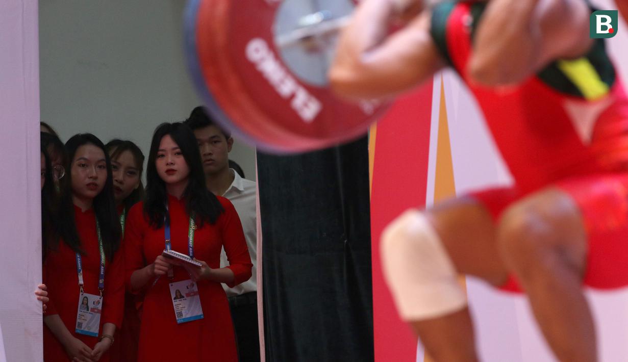 Kelas 73 kg putra di cabang angkat besi SEA Games 2021 menjadi daya magnet para kaum hawa yang bertugas sebagai panitia disebabkan karena diikuti beberapa lifter berparas tampan dengan postur ideal, seperti lifter Indonesia, Rahmat Erwin Abdullah dan lifter Malaysia, Muhammad Erry Hidayat. (Bola.com/Ikhwan Yanuar)