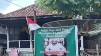 Baliho pemimpin aliran sesat Tasawuf Maqom Hakiki Mutlak yang dipasang di depan rumah warga.