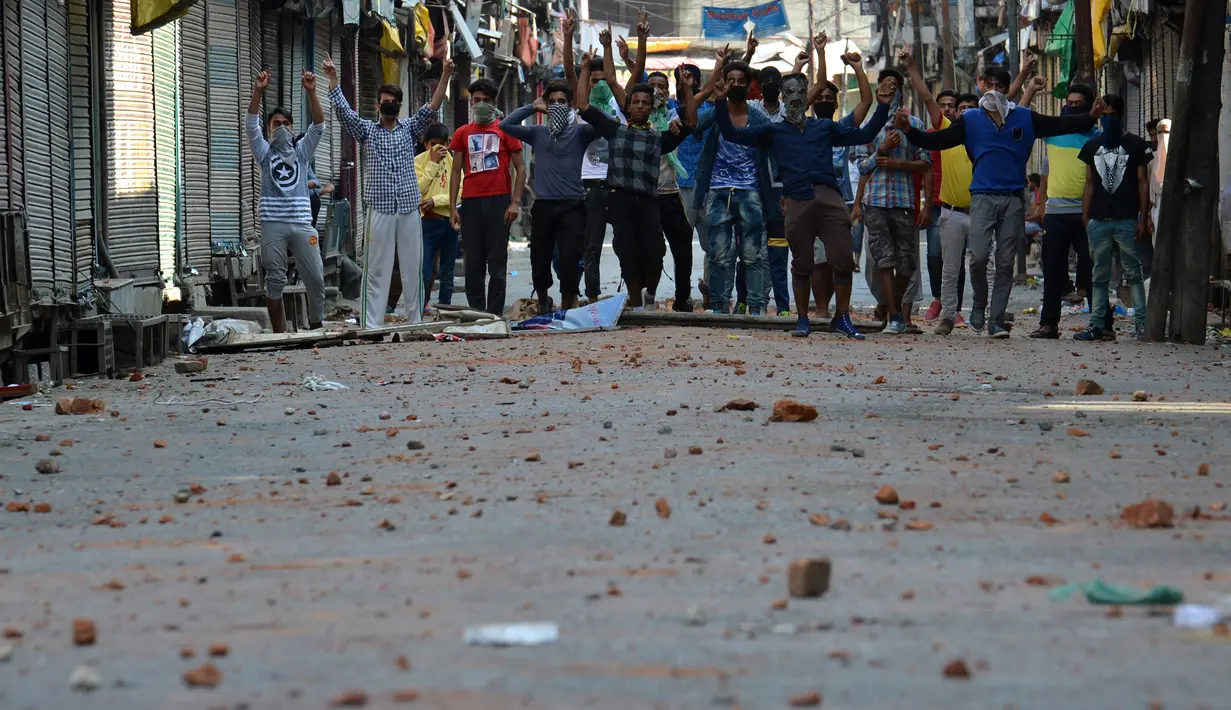 Sejumlah warga Kashmir saat bentrok dengan petugas polisi di Srinagar, India (11/7). Bentrokan bermula karena adanya kasus pembunuhan terhadap seorang pemberontak muda yang populer di India. (AFP PHOTO/Tauseef MUSTAFA)
