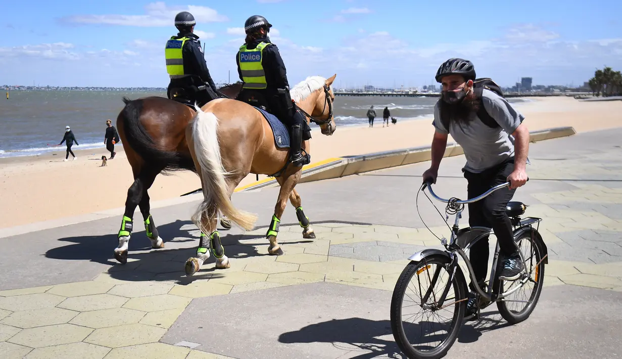 Polisi berpatroli dengan menunggang kuda di sepanjang St Kilda Esplanade di Melbourne (26/10/2020). Pejabat kesehatan Australia melaporkan tidak ada kasus virus corona baru atau kematian di negara bagian Victoria. (AFP Photo/William West)