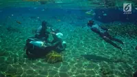 Pengunjung menaiki sepeda motor dalam kolam renang Umbul Ponggok, Desa Polanharjo, Klaten, Jawa Tengah, Minggu (30/9). Umbul Ponggok merupakan mata air yang dimanfaatkan sebagai pemandian dan snorkeling. (Liputan6.com/Gholib)