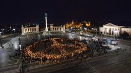 Orang-orang membuat tanda perdamaian dengan lampu saat demonstrasi untuk Ukraina yang diselenggarakan oleh Greenpeace di Heroes Square, Budapest, Hungaria, 9 Maret 2022. Lebih dari 1,5 juta orang telah menyeberang dari Ukraina ke negara-negara tetangga. (AP Photo/Anna Szilagyi)