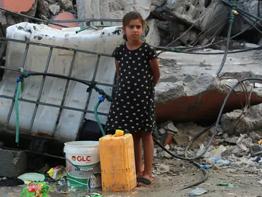 Seorang anak perempuan Palestina bersiap mengisi wadah plastik dengan air di titik distribusi di Khan Yunis di Jalur Gaza selatan pada 17 Oktober 2024. (BASHAR TALEB/AFP)