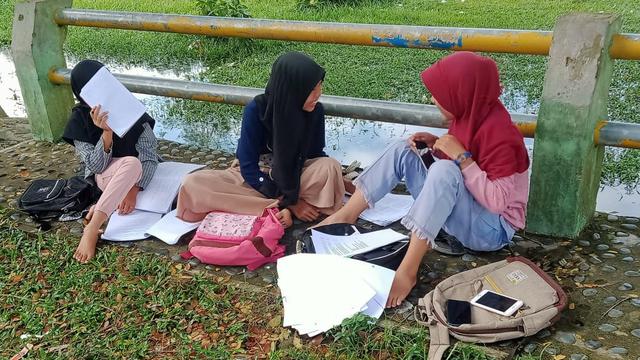 Para pelajar belajar di tepi sungai karena susah sinyal