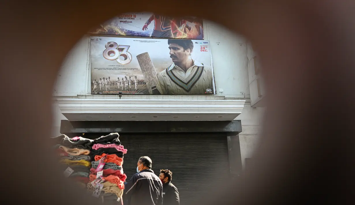 Orang-orang membeli pakaian dari kios-kios yang didirikan di luar gedung bioskop di New Delhi (29/12/2021). Pemerintah Delhi memberlakukan pembatasan fasilitas seperti gedung bioskop, multipleks, dan gym, dan lainya untuk mengekang lonjakan virus corona Covid-19. (AFP Photo/Sajjad Hussain)